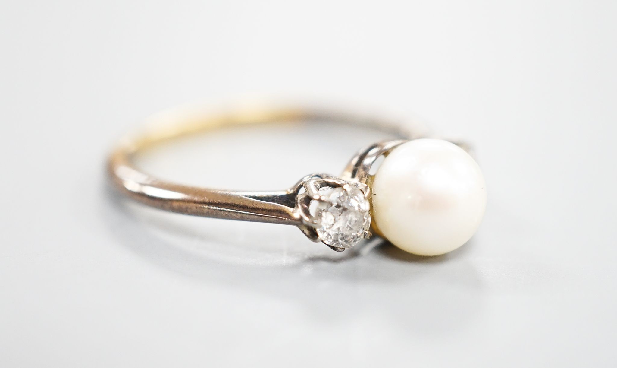 An early 20th century 18ct, single cultured pearl and two stone diamond set ring, size N, gross weight 2.5 grams.